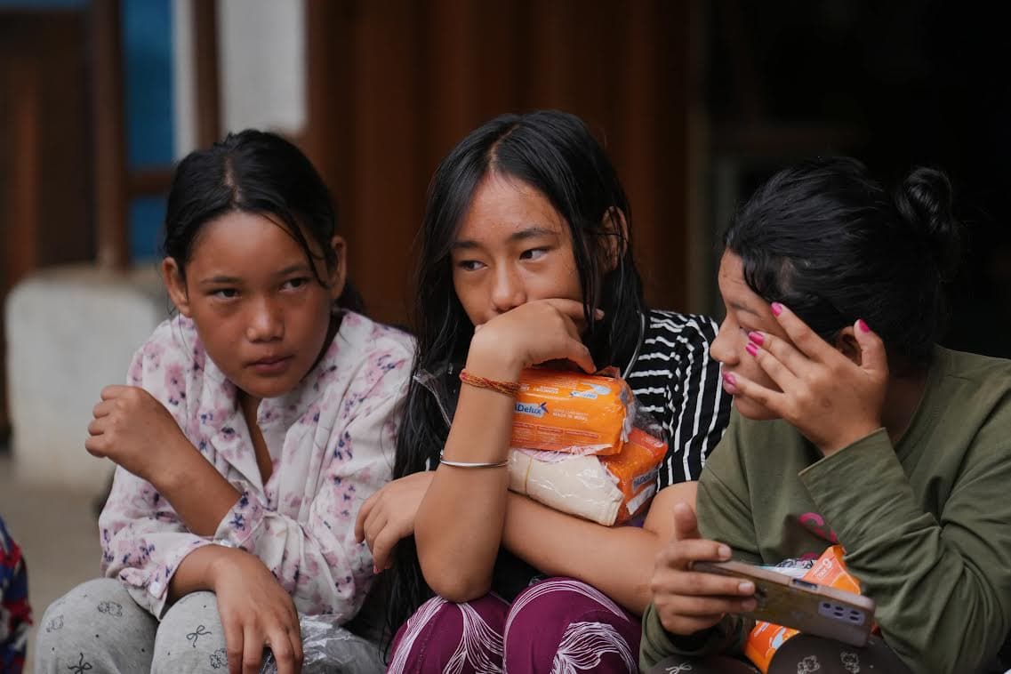 Three girls in Nepal holding donated supply packages